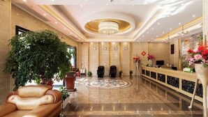 Un vestíbulo de hotel con una recepción, zona de estar y una planta grande en maceta.