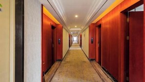 Un largo y estrecho pasillo de hotel con puertas rojas a ambos lados y piso alfombrado.