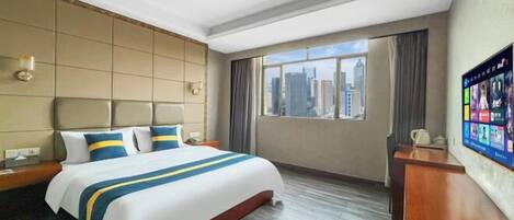 A hotel room with a large bed, a desk, a chair, a TV, and a view of the city.