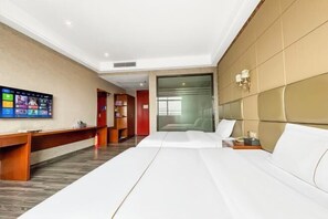 Una habitación de hotel con cama, escritorio, televisor y extintor.