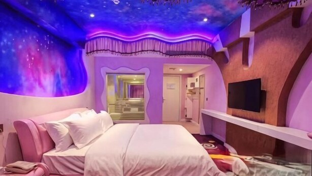 Un dormitorio con cama, tocador y televisor.