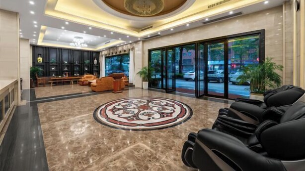 A hotel lobby with a marble floor, a central round table, leather seating, and a large chandelier. - Hedu Hotel (Dongguan Qiaotou) (Dongguan)