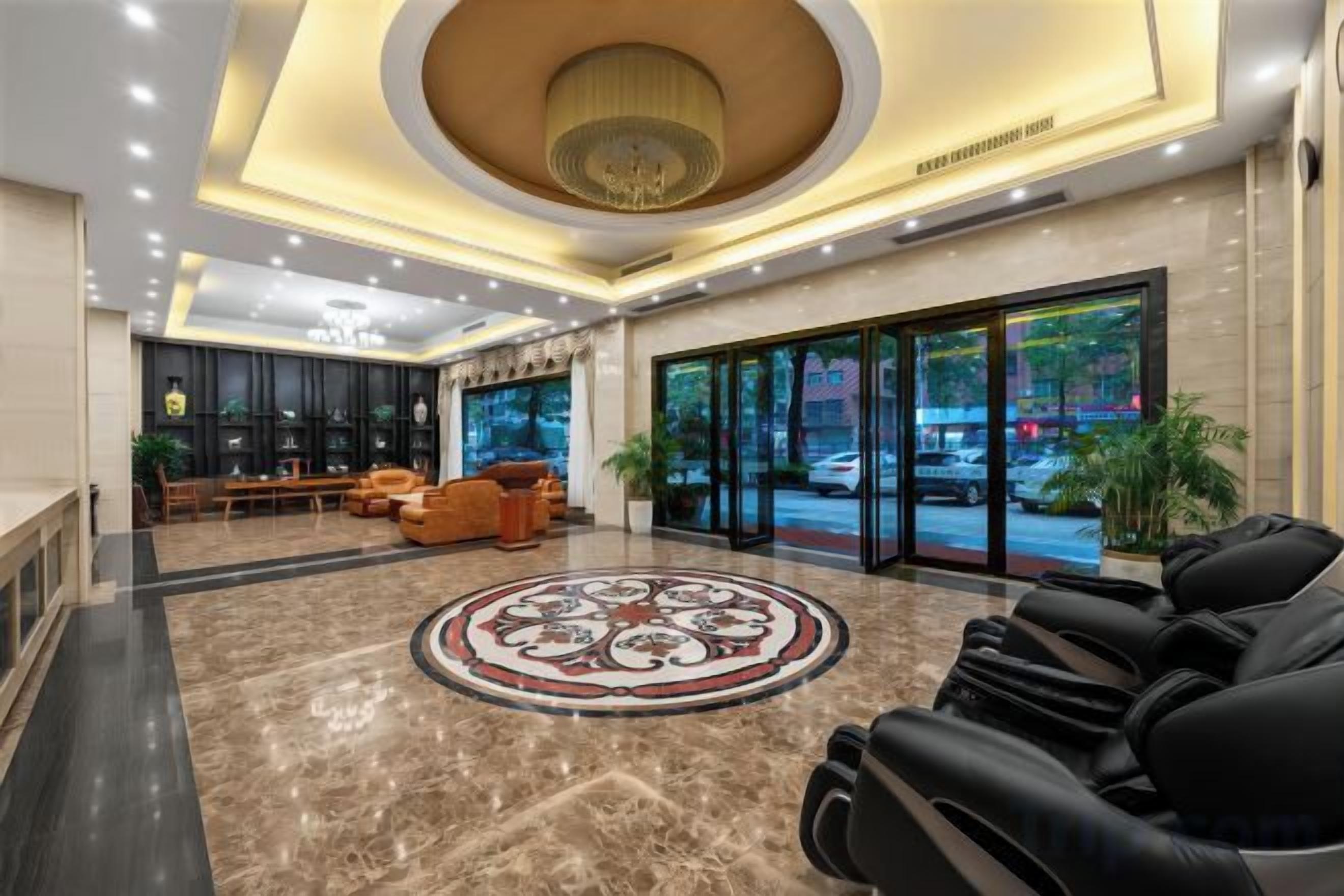 A hotel lobby with a reception desk, seating area, and a large circular patterned floor.