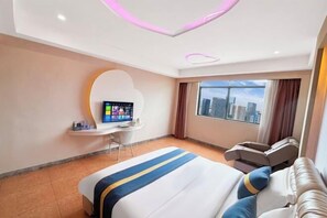A modern hotel room with a bed, a desk with a computer, a massage chair, and a large window with a city view.