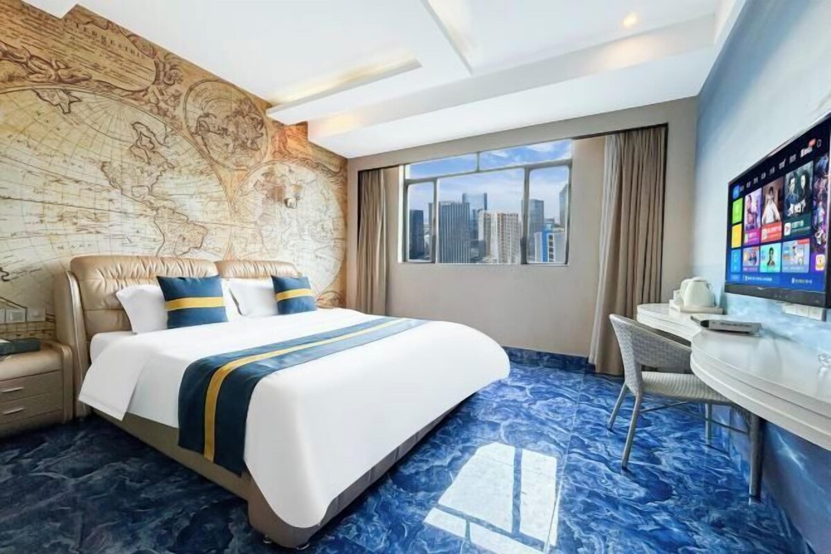 Habitación de hotel con una cama grande, escritorio, televisión y vista a la ciudad.