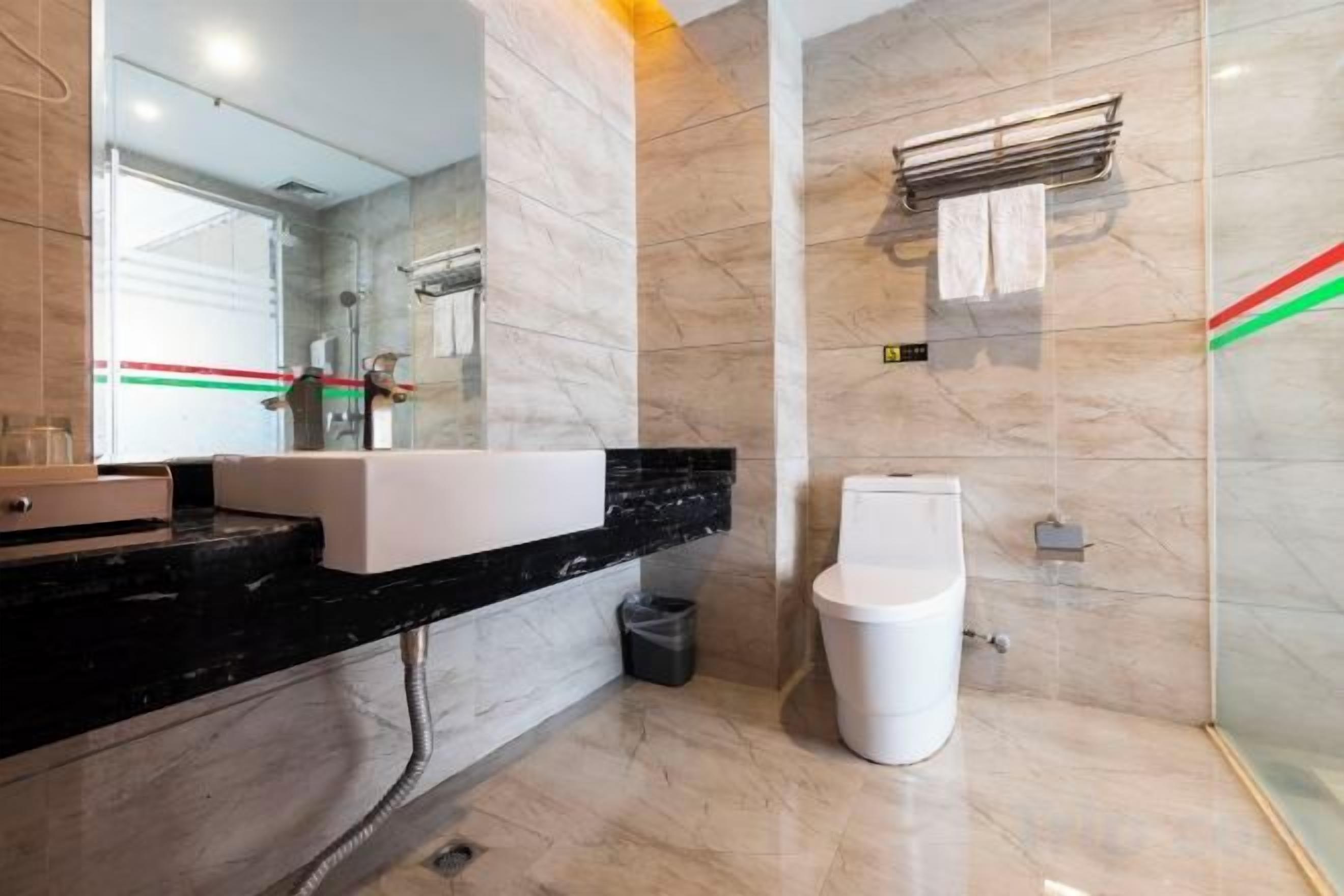 A modern bathroom with a marble sink, a toilet, and a glass shower enclosure.