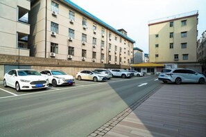 Un estacionamiento con varios autos estacionados frente a un edificio de techo plano y múltiples ventanales.