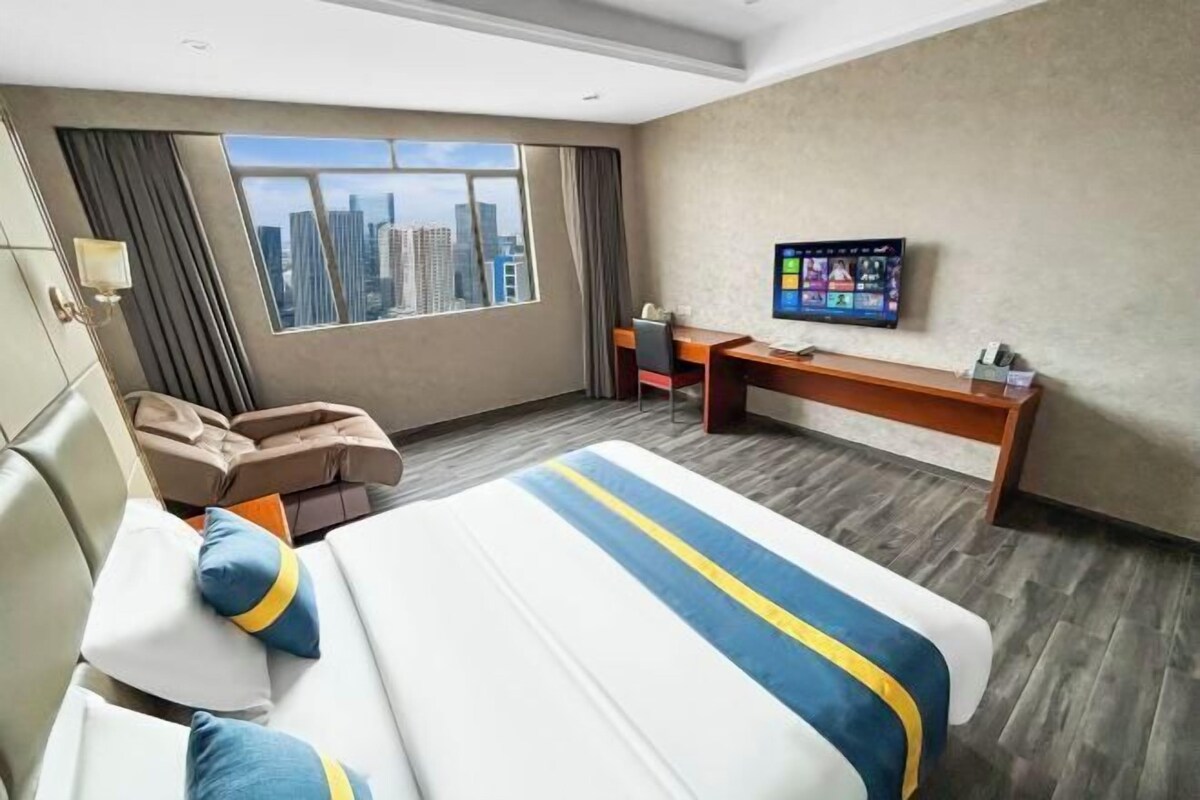 Habitación de hotel con una cama grande, un escritorio, una silla y un televisor.