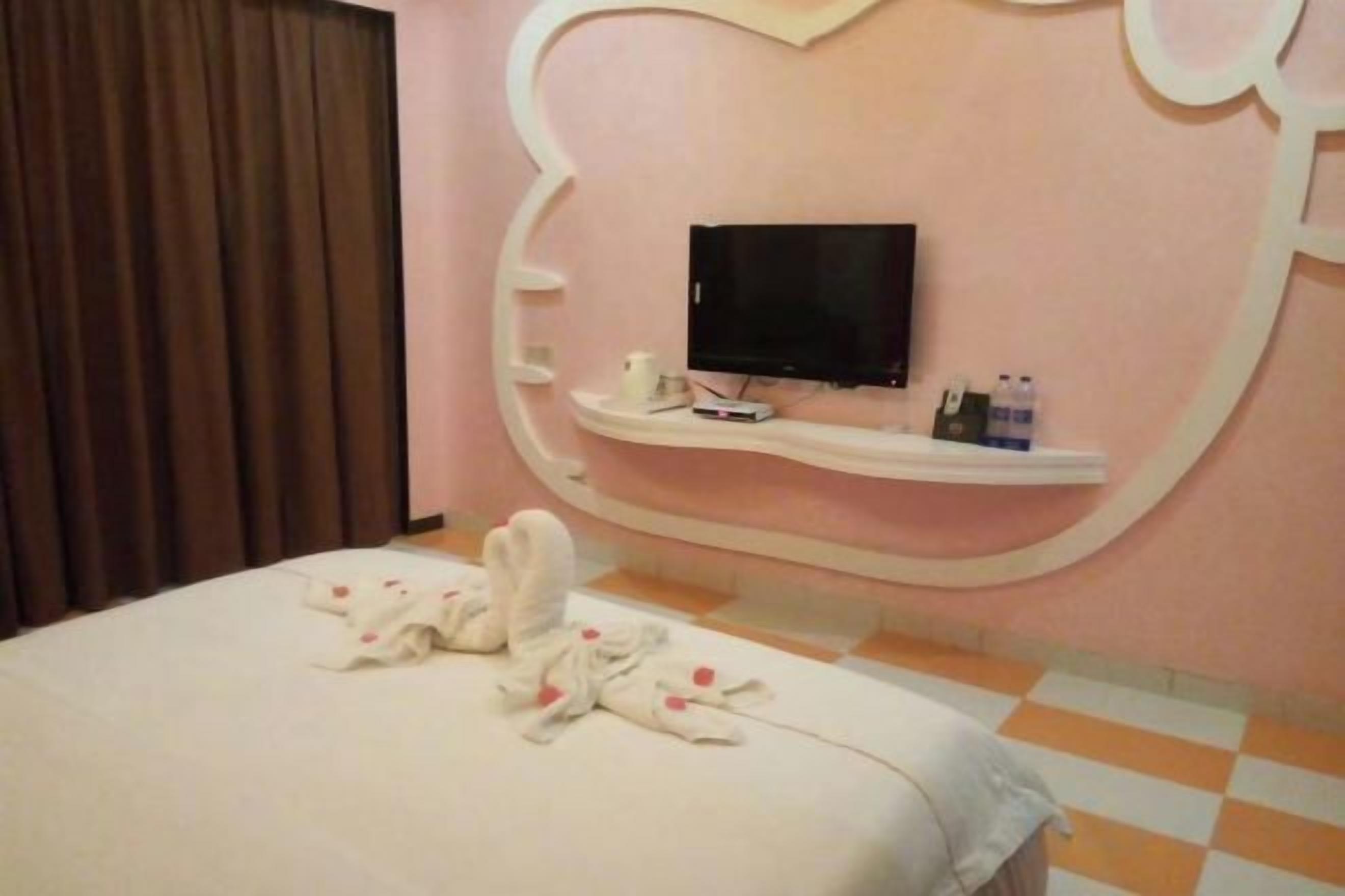 Quarto de hotel com cama, televisão e prateleira com artigos de higiene pessoal.