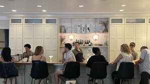 A bar area with white cabinets, a counter with bottles, and a seating area with chairs.