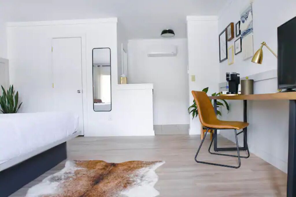 Een moderne, minimalistisch ingerichte slaapkamer met een bed, bureau en stoel.