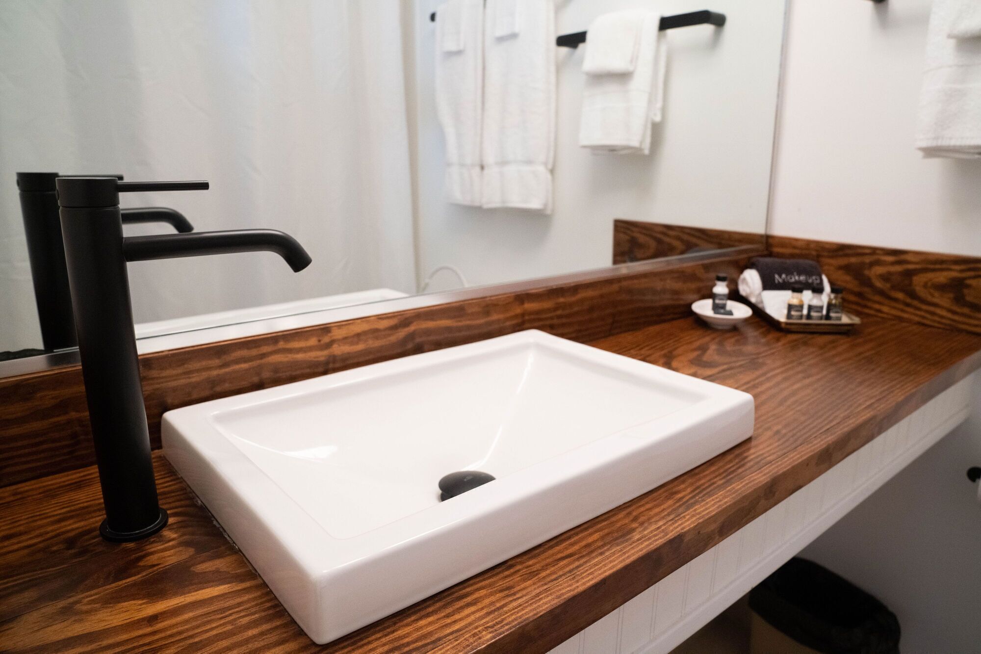 A bathroom with a white sink, black faucet, and wooden countertop.