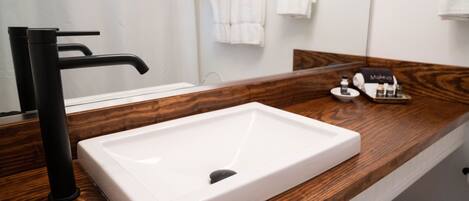 A bathroom with a white sink, black faucet, and wooden countertop.
