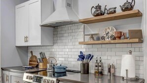 A modern kitchen with white cabinetry, a stainless steel oven, and a countertop with various kitchen items. - Forth House - Butterfly Getaway in Historic SPR! (Jacksonville)