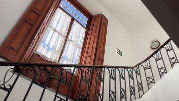 A staircase with a handrail, wooden doors, and a window with curtains.
