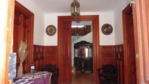 A wooden-paneled hallway with a dining table and chairs, a broom, and a lantern. - Elegant Manor House near Alcalá del Jucar with Piano. (Pozo-Lorente)
