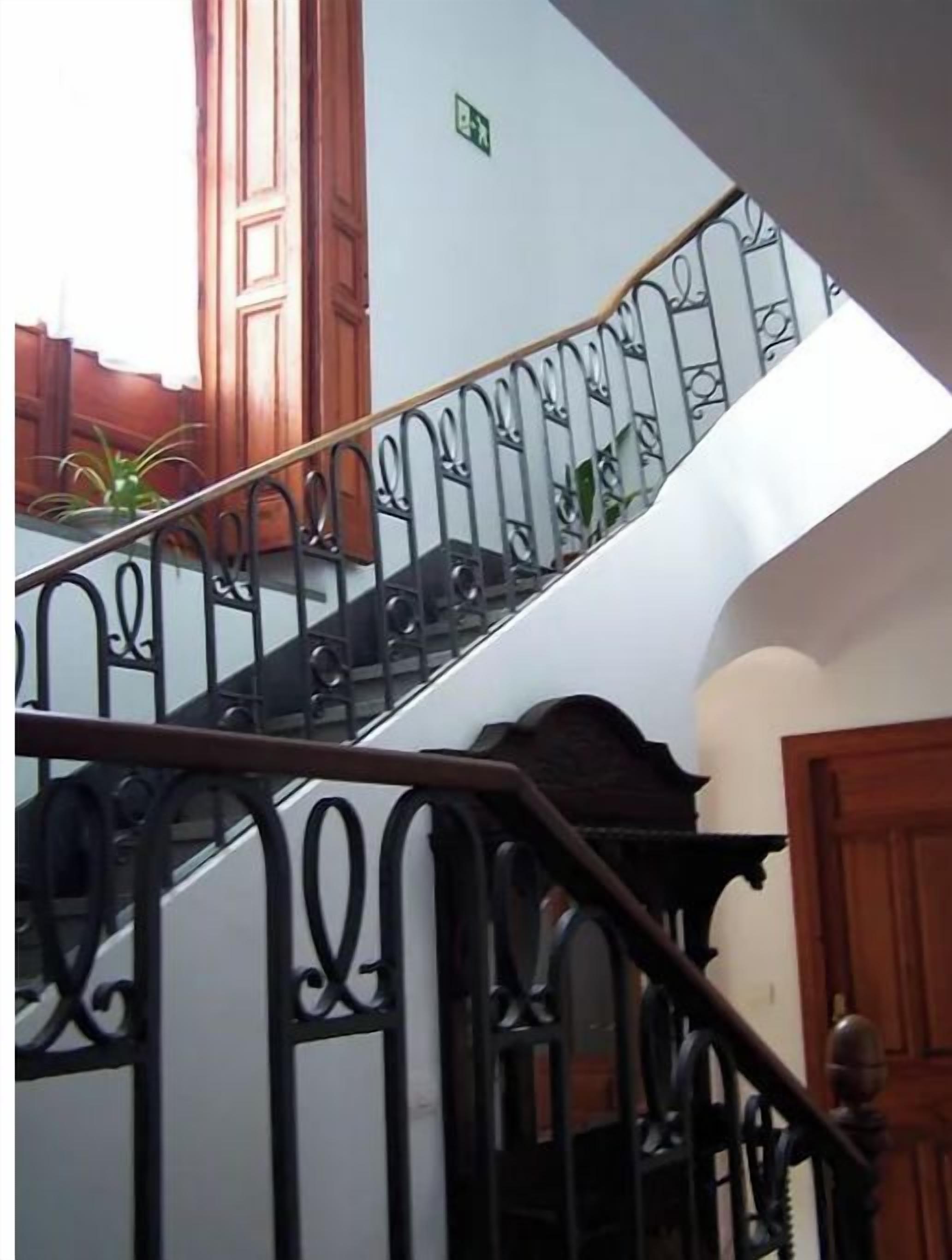 Una escalera con barandillas negras ornamentadas y puertas de madera.