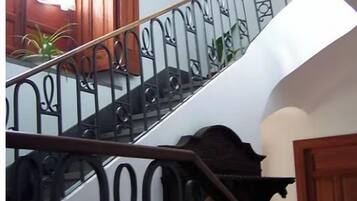 Una escalera con barandillas negras ornamentadas y puertas de madera.