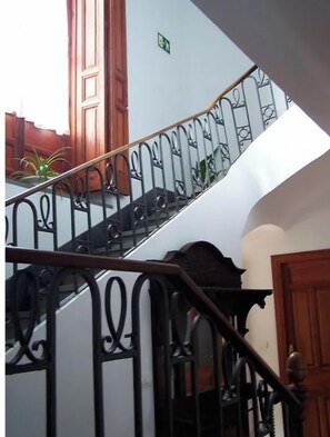 Una escalera con barandillas negras ornamentadas y puertas de madera.