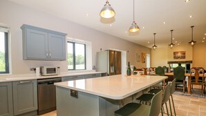 A modern kitchen with grey cabinets, a central island, bar stools, and pendant lighting. - Ghyll Park Farm (Heathfield)