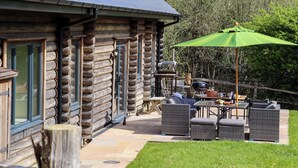 A log cabin with a patio area featuring outdoor furniture and a grill. - Ghyll Park Farm (Heathfield)