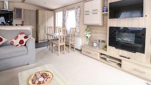 Ein modernes Wohnzimmer mit einer Couch, einem Esstisch, Stühlen, einem Fernseher und einem Kamin.