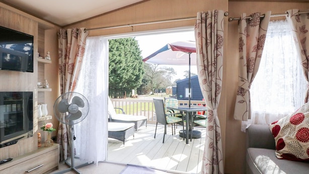 Ein gemütlicher Wohnbereich mit Fernseher, Ventilator und Sitzgelegenheiten.