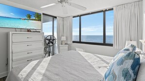 A bedroom with a bed, a ceiling fan, a dresser, a TV, and a view of the ocean. - Sands Beach Club II 625 - Ocean Front 2 Bed/2 Bath Condo - Amenities: Pools, Hot Tub & Tennis Court (Myrtle Beach)