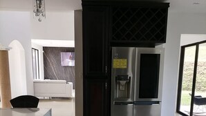 A modern kitchen with a stainless steel refrigerator, a built-in oven, and a water dispenser. There is a marble countertop and a black cabinet. - Luxury Villa, 20 minutes from SJO airport , Gated community (Provincia de Alajuela)