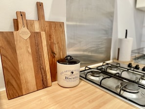 A kitchen counter with a wooden cutting board, a jar labeled "The Artisan Kitchen," and a gas stove. - Waterloo Luxury Apartment (London)