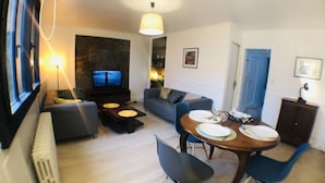 Un salon moderne comprenant un téléviseur, un canapé, une table à manger et des chaises.