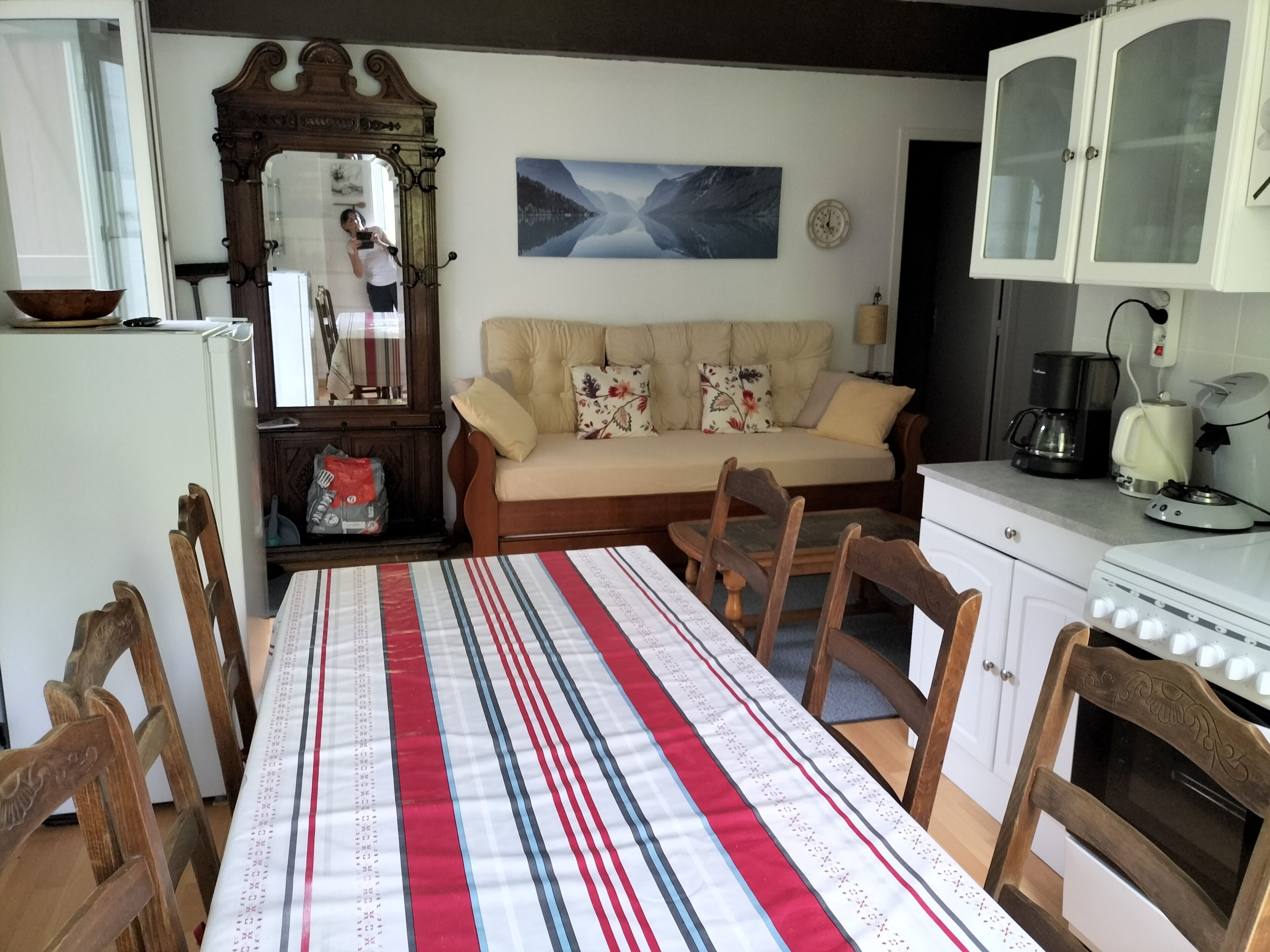 Ein Essbereich mit Tisch, Stühlen, einer Couch, einem Schrank und einem Spiegel.