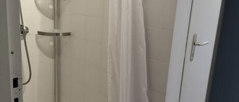 A shower with a white curtain, a handheld showerhead, and a built-in seat.