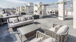 A rooftop terrace with outdoor seating, including a sofa and chairs, and a small table. - Livensa Living Studios Valencia Marina Real (Valencia)