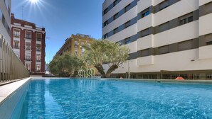 A swimming pool with clear blue water, surrounded by buildings. - Livensa Living Studios Valencia Marina Real (Valencia)