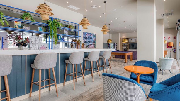 A modern bar area with wooden stools, a pool table, and hanging pendant lights. - Livensa Living Studios Valencia Marina Real (Valencia)