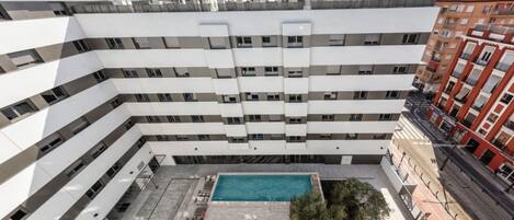 A multi-story building with a rooftop pool and outdoor seating area.