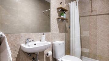 Un baño moderno con lavamanos, inodoro y ducha.