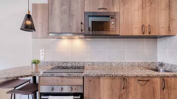 A modern kitchen with wooden cabinets, a built-in microwave, granite countertop, and a stainless steel sink.