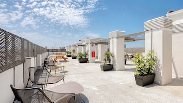 Une terrasse sur le toit, avec des sièges en plein air, des plantes en pot et un ciel dégagé.