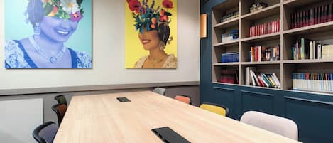 A conference room with a long table, chairs, and a bookshelf filled with books.