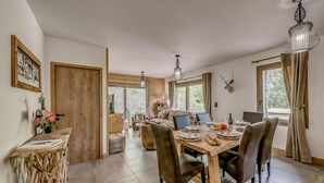 A dining area with a wooden table set for four, surrounded by chairs. There is a wooden bench with a vintage sign, a small table with a vase of flowers, and a wall-mounted deer head decoration. - Ground floor, terrace, tv, ski locker, 78m², Champagny-en-Vanoise (Champagny-en-Vanoise)