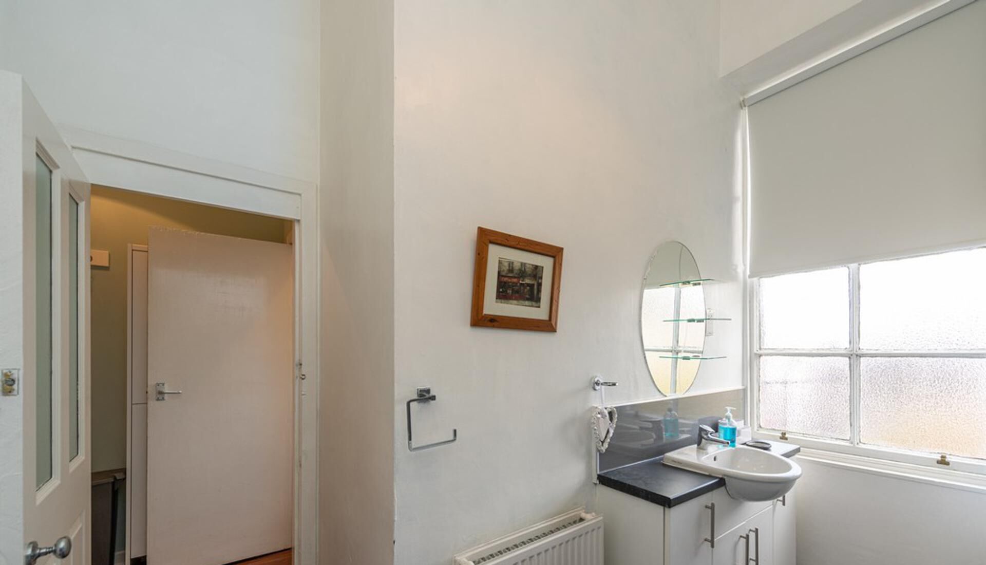 Un baño con lavabo, espejo y ventana.