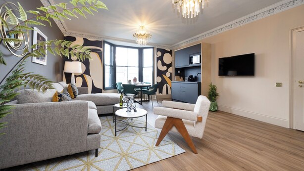 Uma sala de estar moderna com sofá, poltrona, mesa de centro e um lustre.