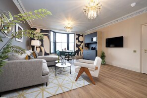 A modern living room with a sofa, armchair, coffee table, and a chandelier.