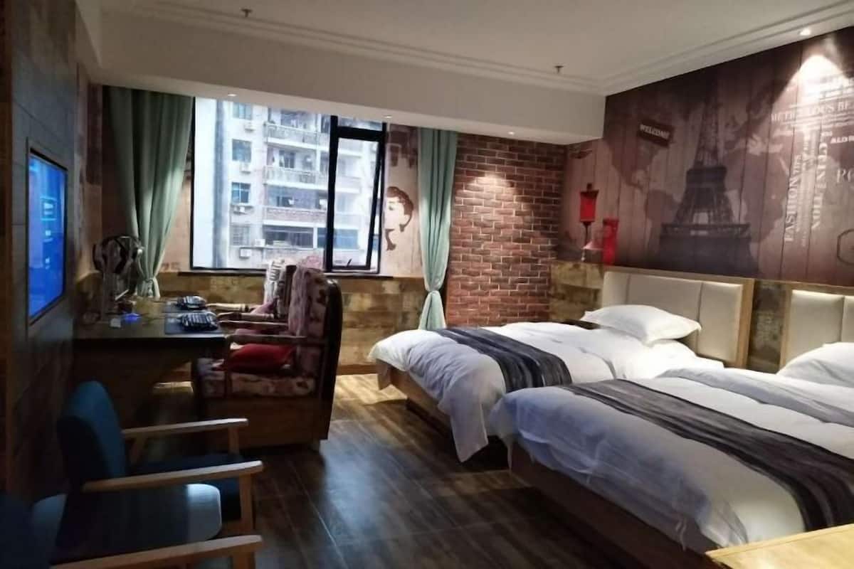 A hotel room with a bed, a desk, a chair, a TV, and a large window with curtains.