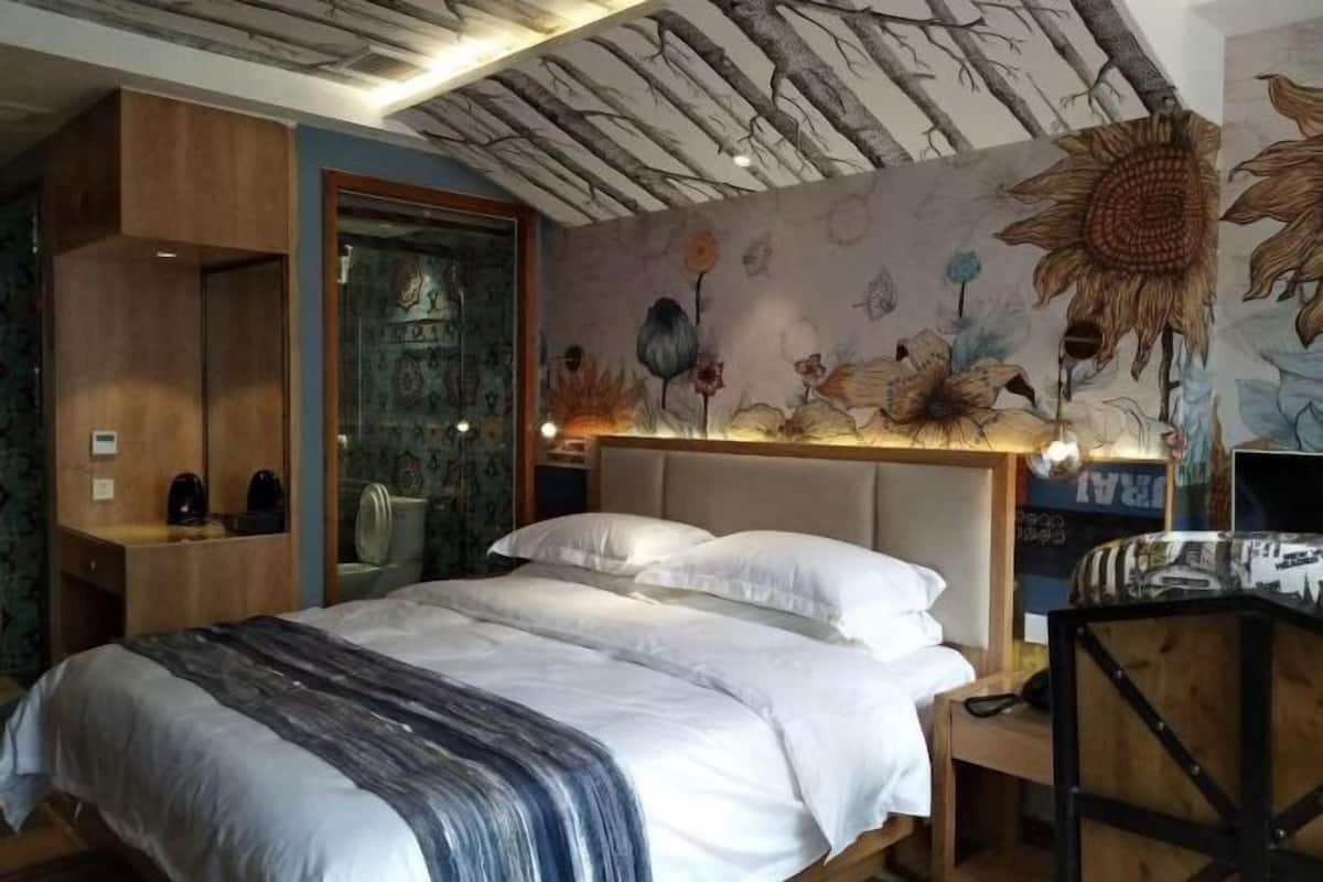 A bedroom with a bed, a wooden headboard, a nightstand, and a wall mural.