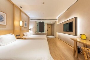 Habitación de hotel con dos camas, televisión, escritorio y cafetera.