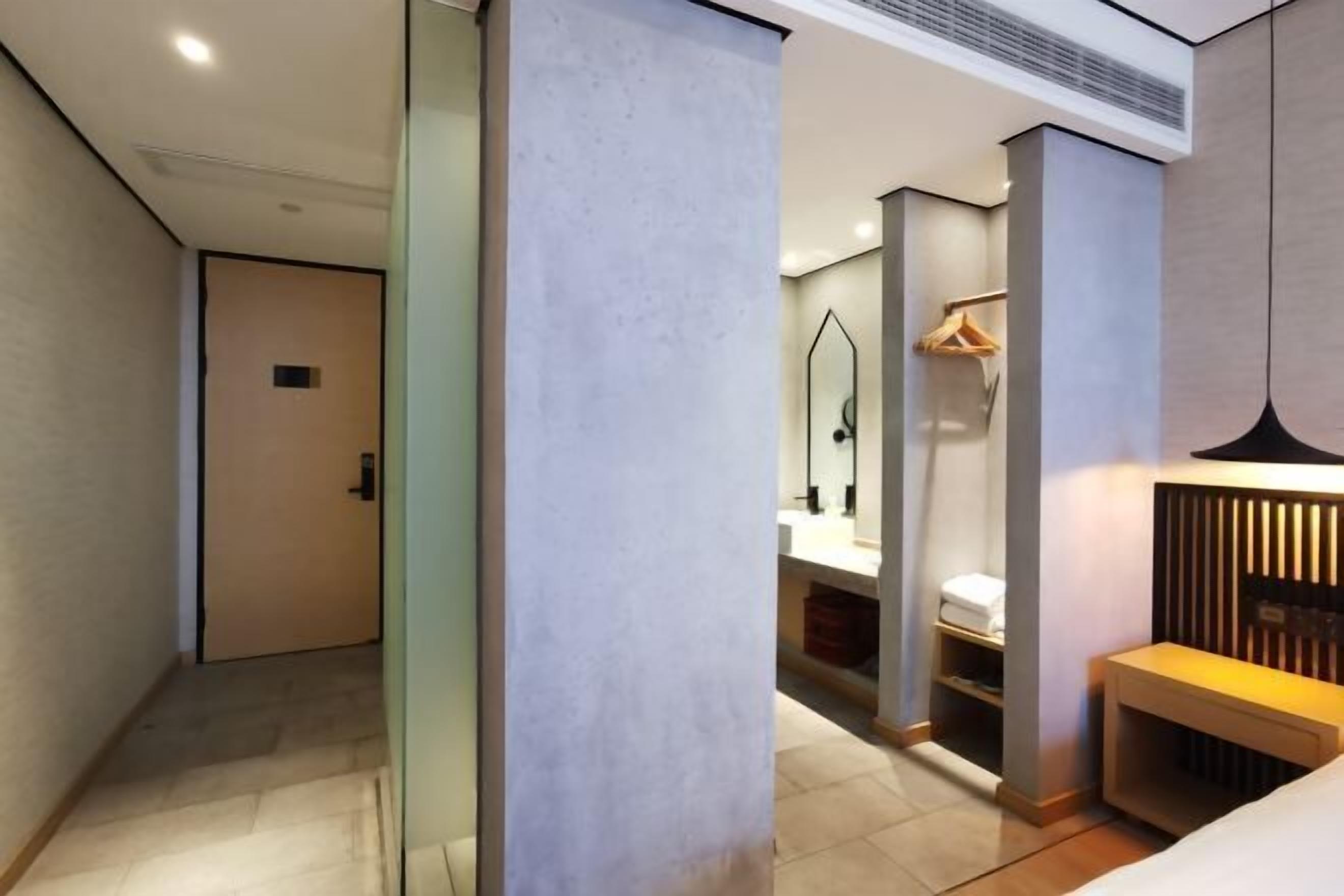 Ein modernes Hotelzimmer mit einem großen Spiegel, einem Nachttisch und einem Kleiderschrank.
