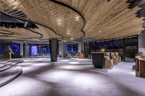 Un vestíbulo espacioso con un techo de madera curvada, grandes columnas y una zona de estar central.